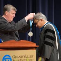 President Emeritus Haas placing a medallion over a faculty member on stage.